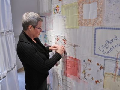 Astrid Gjesing broderer videre på ALT FORLADT på et væv af brugte herre-, dame- og børnelommetørklæder.