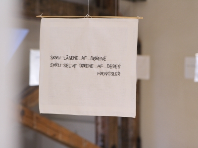 Enkelthængende, bevægelige, nye damelommetørklæder med håndbroderede tekster.